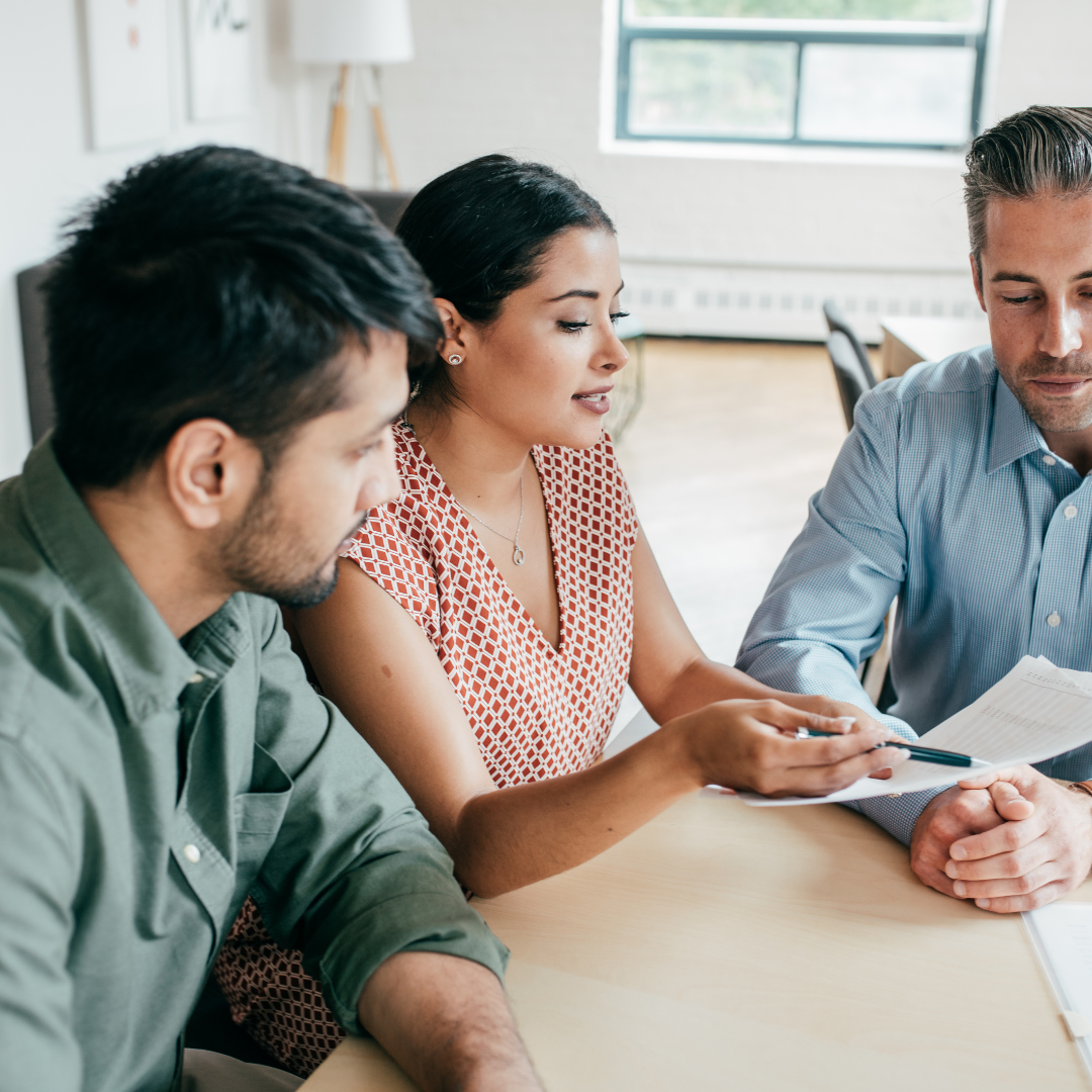 Employer reviewing group benefits paperwork with two employees at a table.
